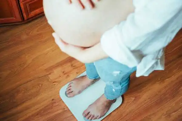 Image of woman weighing herself and experiencing weight gain through pregnancy Ledbury